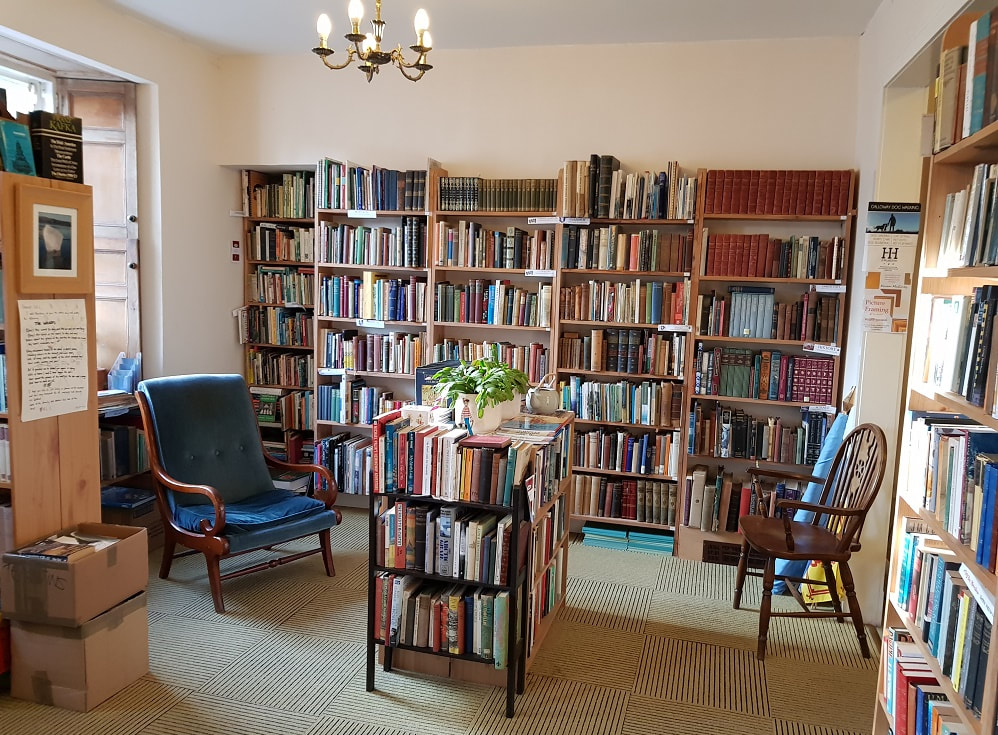 A room with rows of shelves filled with books and two armchairs