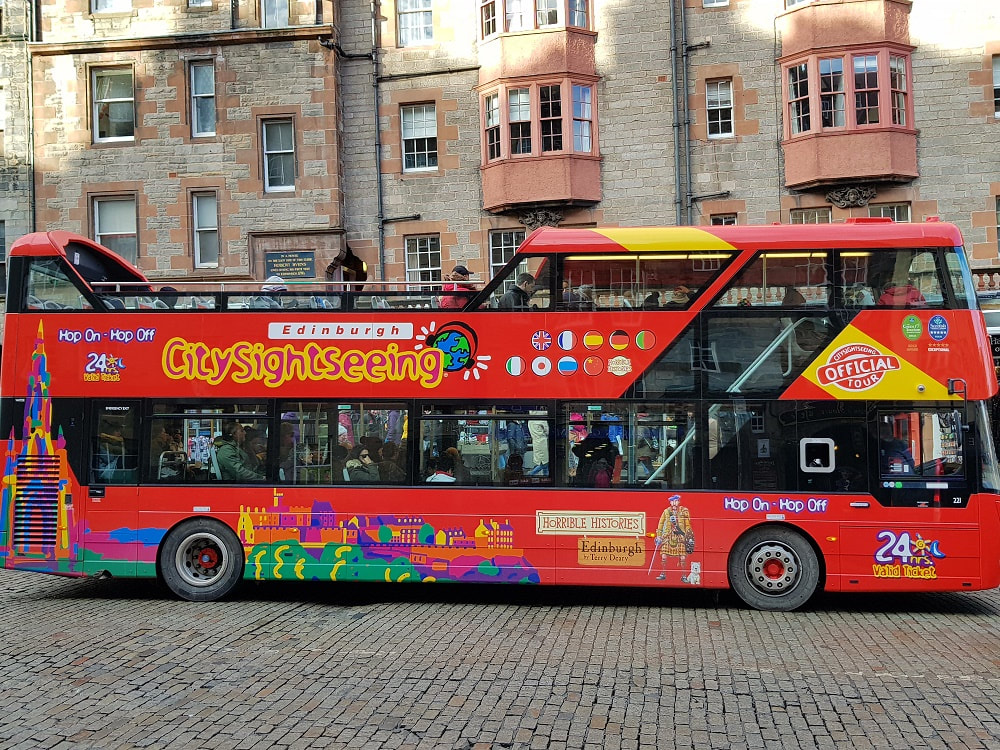 A red open top bus with the words Hop on Hop Off Edinburgh CitySightseeing on the side