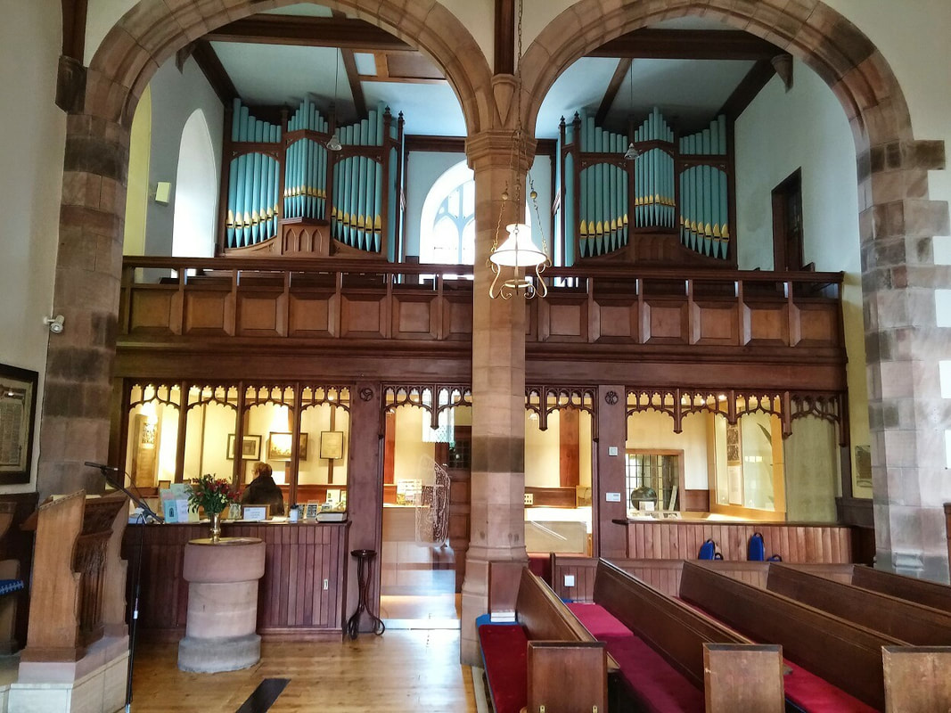 The interior of a church with pews in the foreground and an organ on the far wall