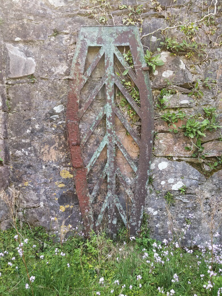 A metal mortsafe propped against a stone wall