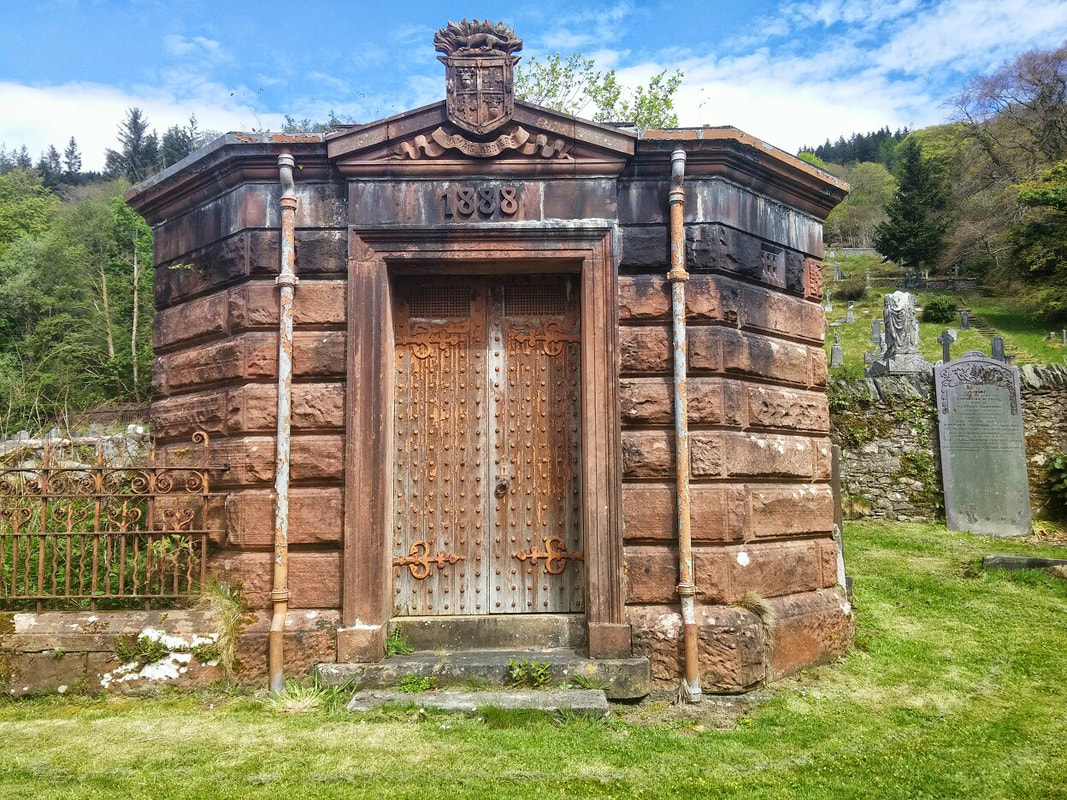 A brown stone vault with an oak door and the Douglas family coat of arms