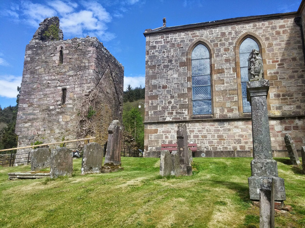 Graveyard with corner of church showing and a ruined stone tower