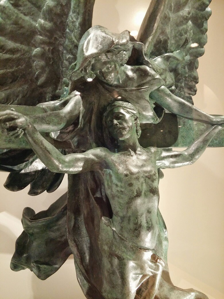 A sculpture of Jesus on the cross with an angel holding his hands