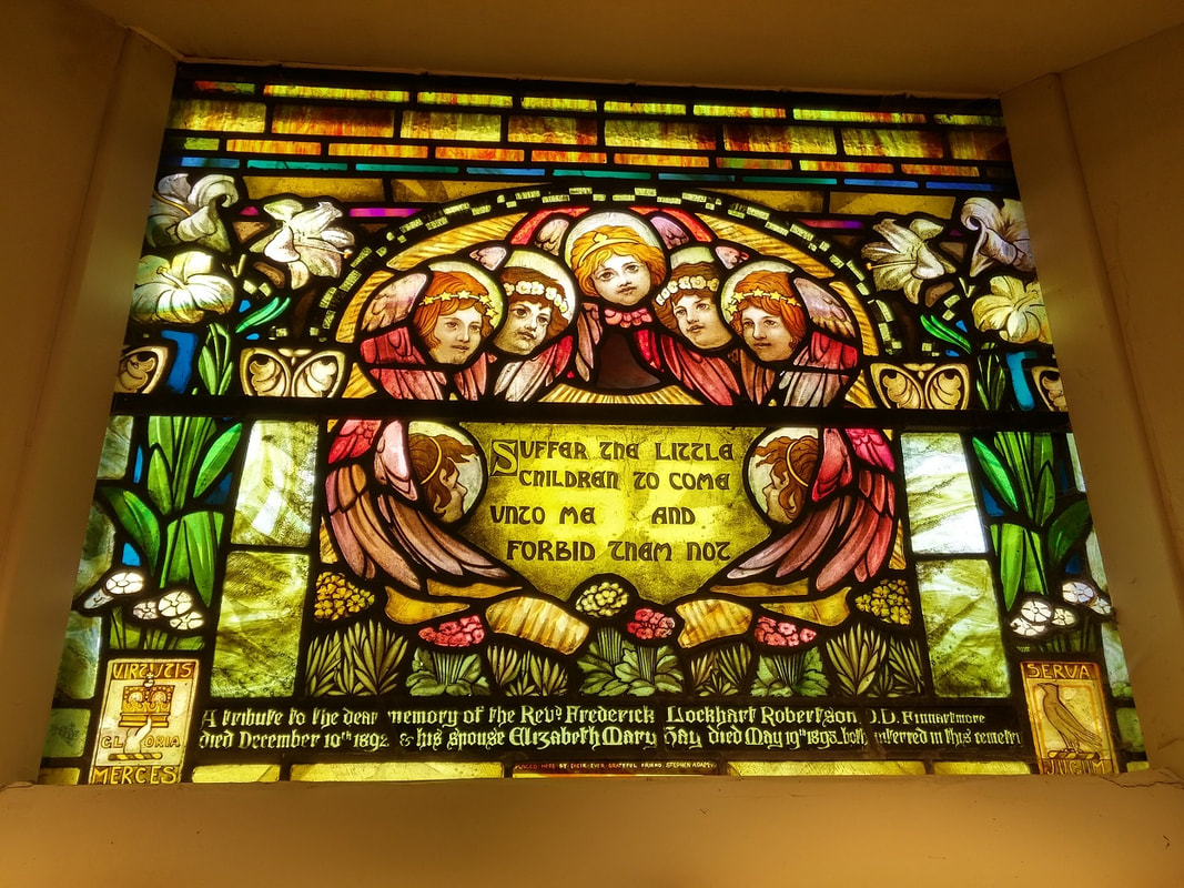 Stained glass window with seven angels in the centre surrounded by flowers