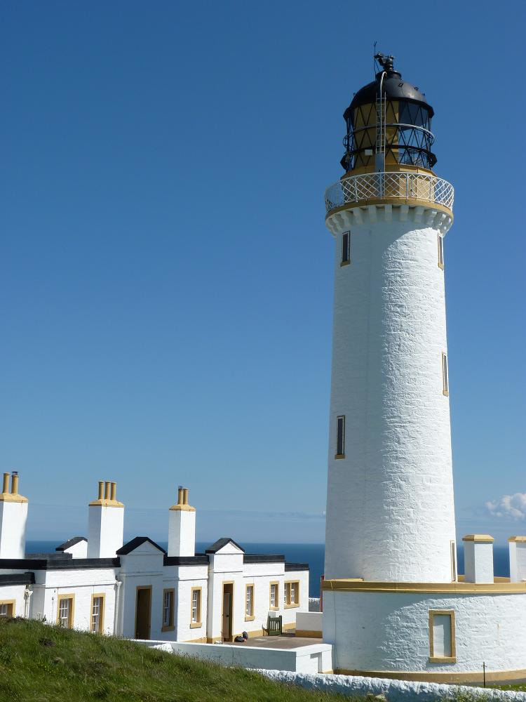A white washed lighthouse overlooking the sea.