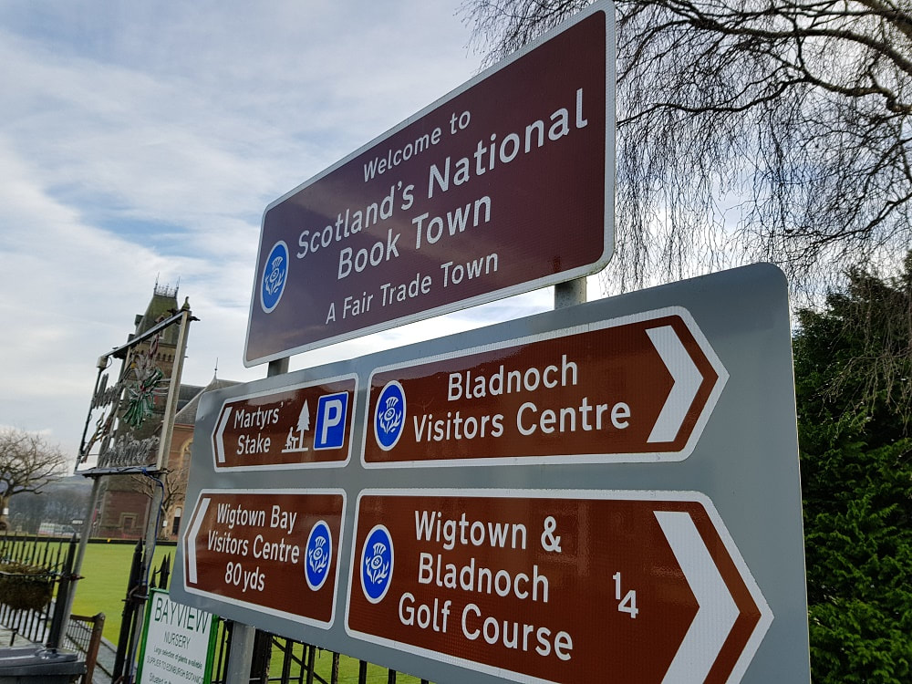 Brown sign reading Scotland's National Book Town, A Fair Trade Town