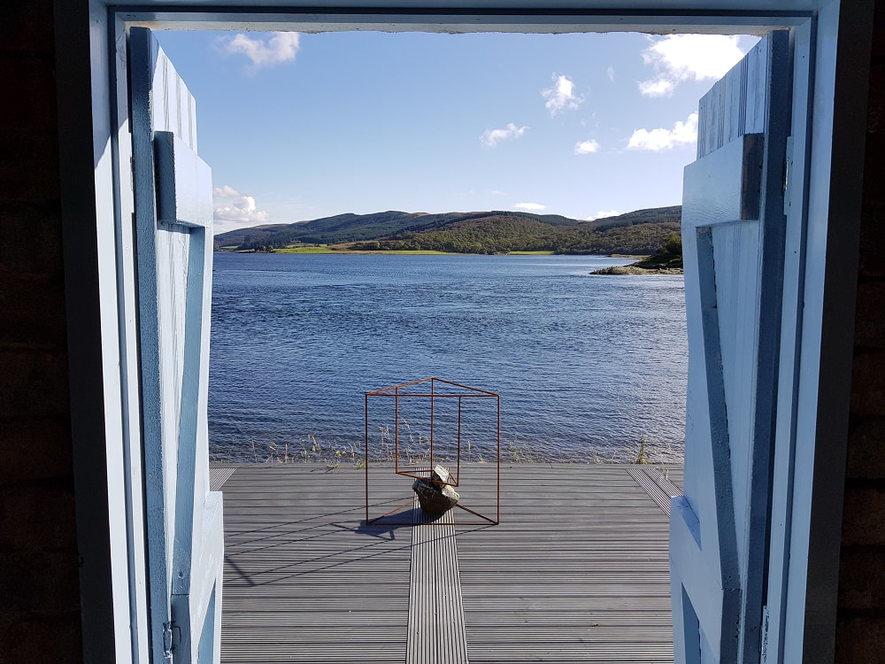 Two open blue wooden doors with a view of water and an island