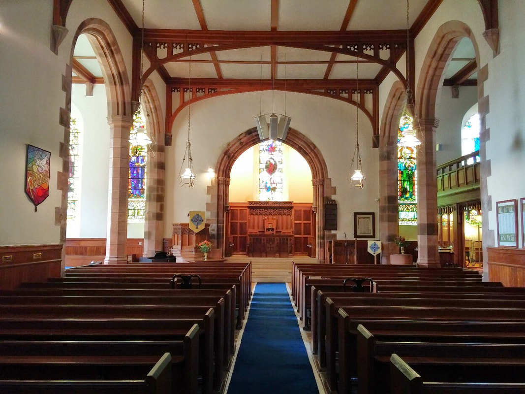Brightly lit interior of a church with wooden pews on either side and an altar in the background